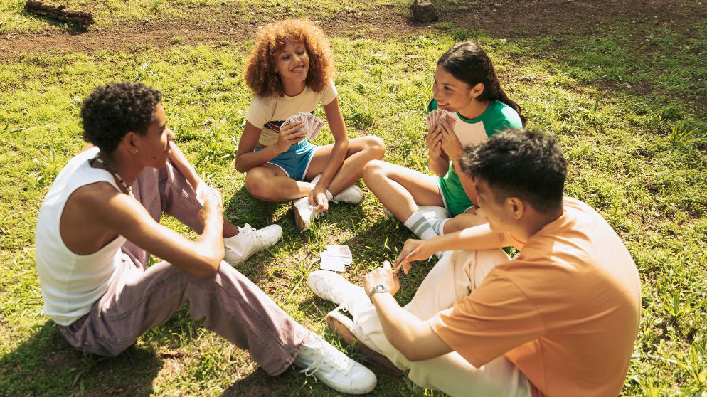 Jeunes jouant aux cartes sur l'herbe